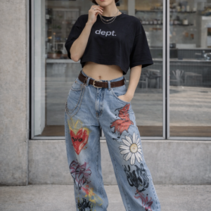 Modelo con ropa de Urban Mirage: top negro cropped y jeans anchos con estampado gráfico y cadenas en cinturón estilo streetwear.