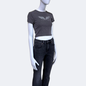 Manequí posando de manera lateral con vaqueros flare negros de tiro medio de la marca Urban Mirage, combinados con camiseta cropped gris. El estilo es casual con acabado moderno y silueta acampanada. Ideal para outfits streetwear.